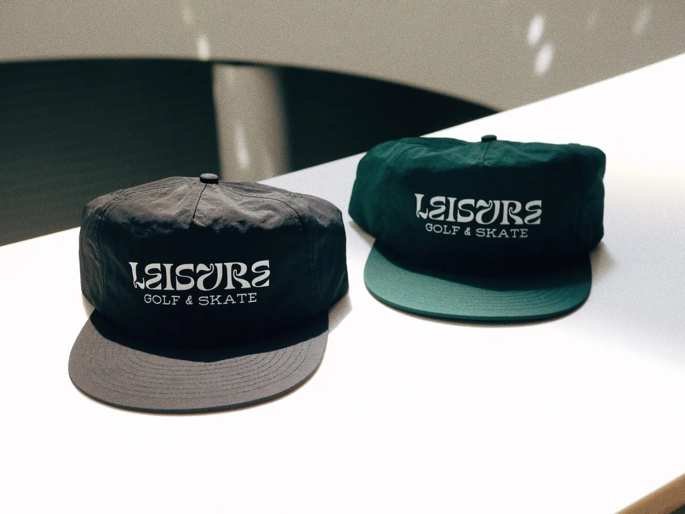 Two Leisure nylon camp caps, forest green and black