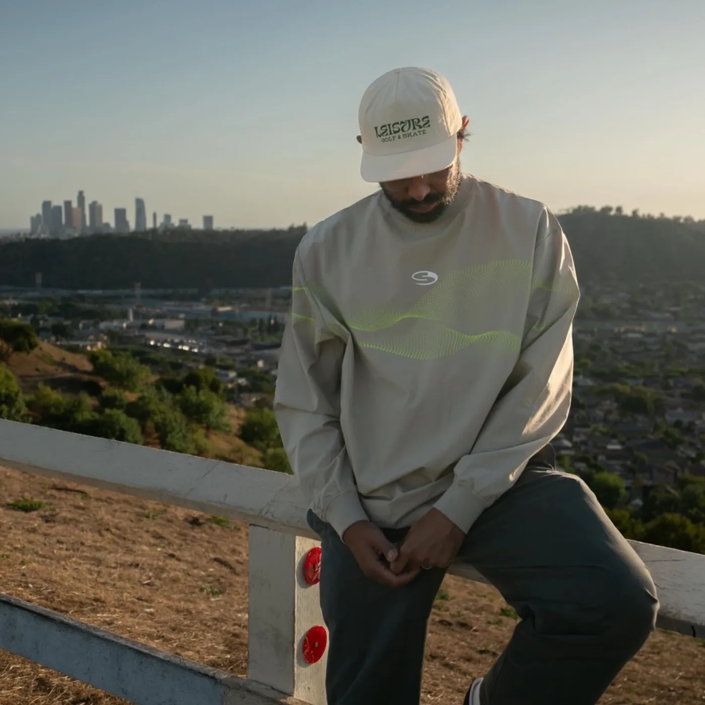 Wearing a Leisure cap and technical crewneck above the Los Angeles skyline