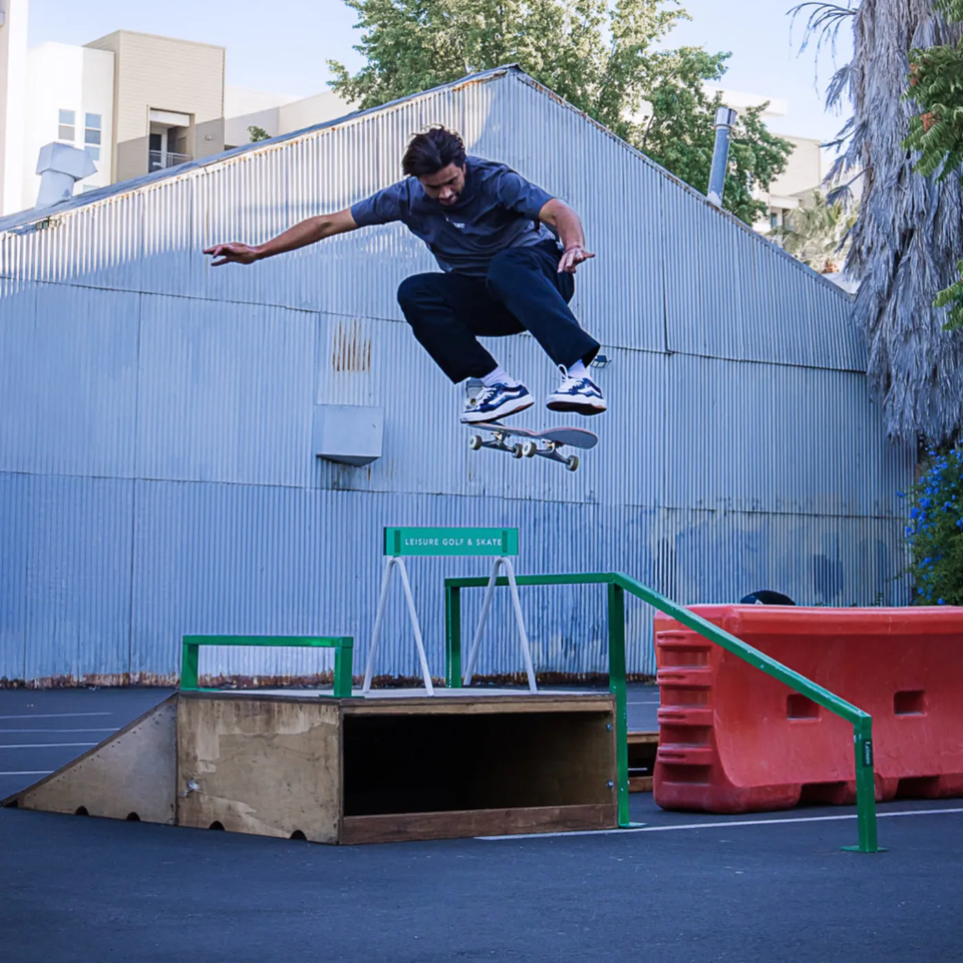 Skater ollies over a box painted Leisure Golf and Skate